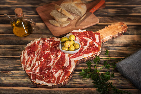 Guitar-shaped board with Serrano ham with bread, olive oil and olives