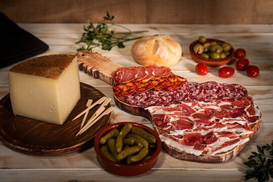Boards with cured meats, ham and cheese, accompanied by olives, pickles and bread, gastronomic still life.