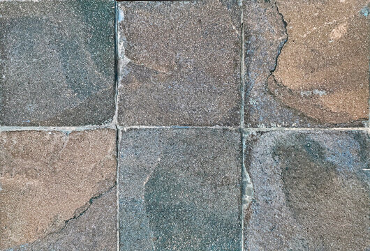 Unique natural rough slate stone wall texture in mix of brown, terracotta, blue, and grey with random abstract veins. Honed and rough outdoor stone cladding tiles wall seamless background.