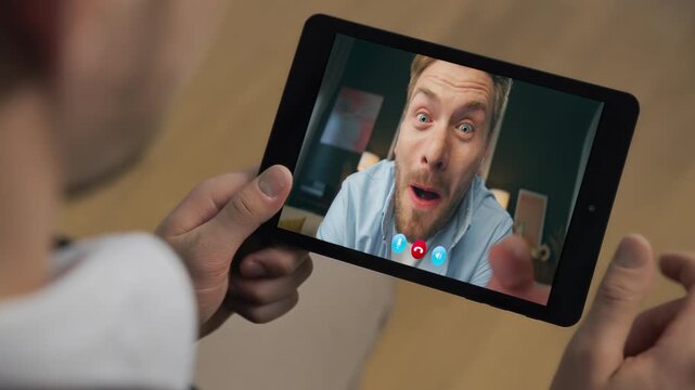 Surprised distant colleagues call tab at apartment closeup. Man holding tablet