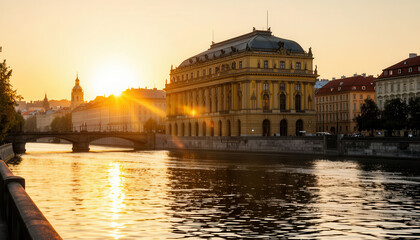 Fototapeta premium The sunset casts a warm glow over the river beside the historic building. The building and river reflect the golden colors as the day transitions into night.