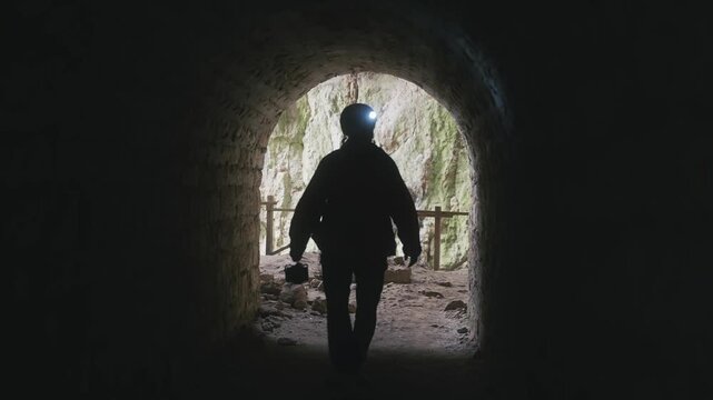 Geologist Explorer's Journey: Light at End of Dark Cave Tunnel