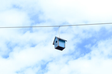 Obraz premium Tiny blue birdhouse dangles from a single wire