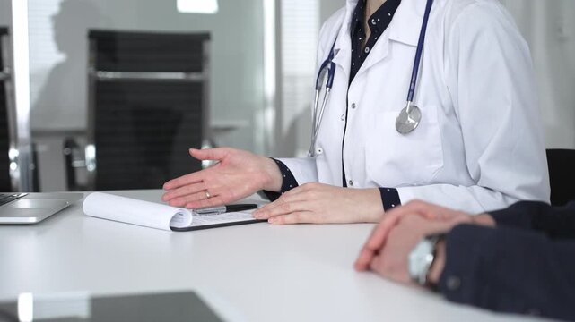 Experienced female doctor consulting patient man, providing medical advice and writing prescription during hospital appointment. Medicine, healthcare and science concept