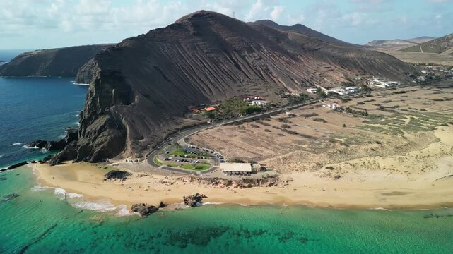Aerial view of drone flying over golden sand beach with a small rock island in Porto Santo, Madeira, Portugal. Portuguese paradise with clean transparent water.