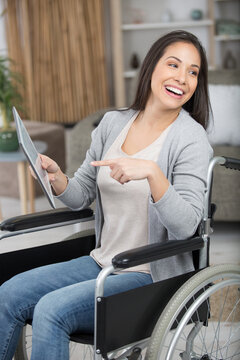 cheerful woman in a wheelchair pounting to her tablet screen