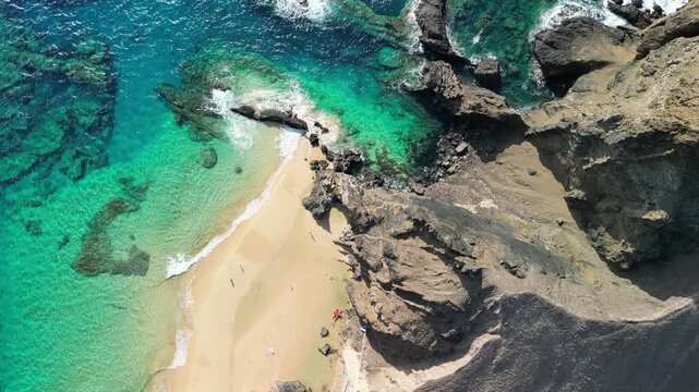 Aerial view of drone flying over golden sand beach with a small rock island in Porto Santo, Madeira, Portugal. Portuguese paradise with clean transparent water.