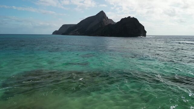 Aerial view of drone flying over Ilheu da Cal, a small rock island in Porto Santo, Madeira, Portugal. Portuguese paradise with clean transparent water.