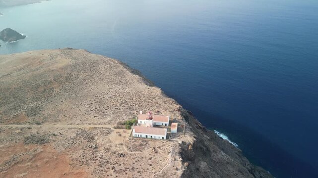Aerial drone view over a rocky tiny island (Ilheu) with a light house. Volcanic scenic view in Porto Santo island, Madeira, Portugal