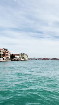 View from water of the Giudecca Canal in Venice with buildings lining the waterway