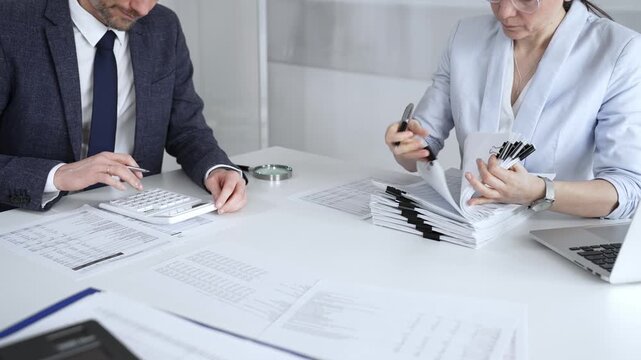 Professional accountant team analyzing corporate financial data, managing paperwork, and preparing tax reports, collaborating on bookkeeping and auditing tasks at a desk. Audit and taxes