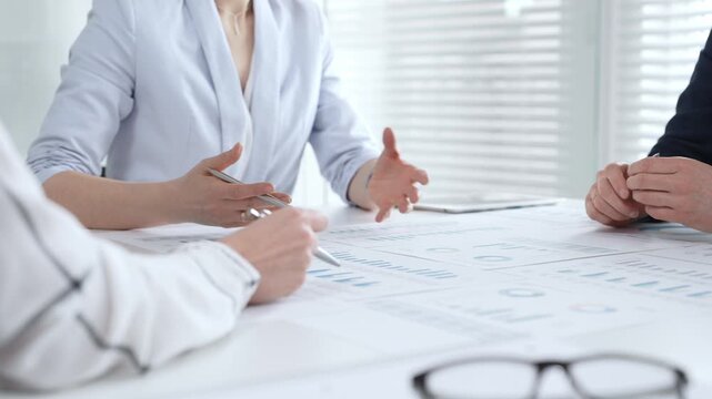 Businesswoman signing important contract documents at a meeting. Confirming agreement and partnership details while colleagues show support
