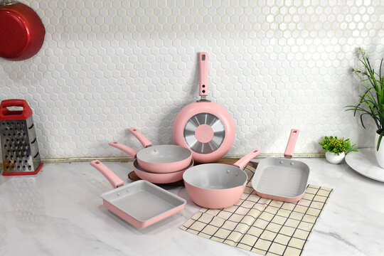 Kitchen cookware styling with pink pots and pans and plants.