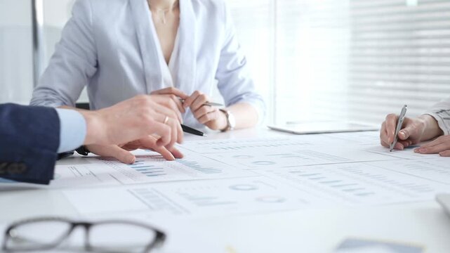 Businesswoman signing important contract documents at a meeting. Confirming agreement and partnership details while colleagues show support