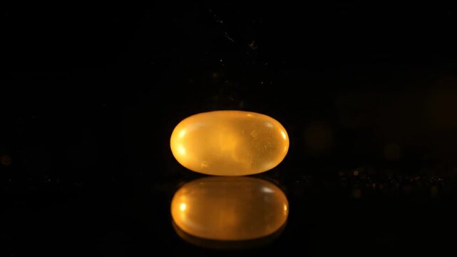 Illuminated capsule reflecting on a dark, glossy surface