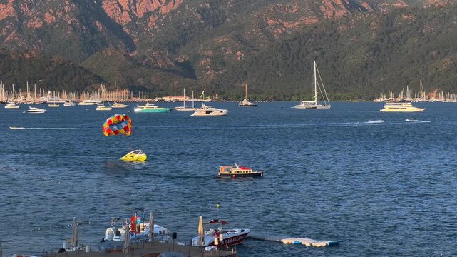 Beautiful day on the water with boats sailing and parasailing flying in the sky. Marmaris Resort seems like a great place for a day out on the water. Mountains in the background are covered in green