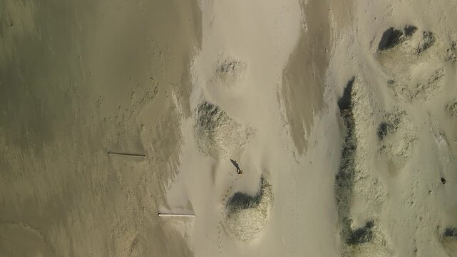 Aerial footage of a lone person walking along Bunes beach, next to Vindstad in Lofoten, Norway, on a sunny day, drone footage, 4k 30fps