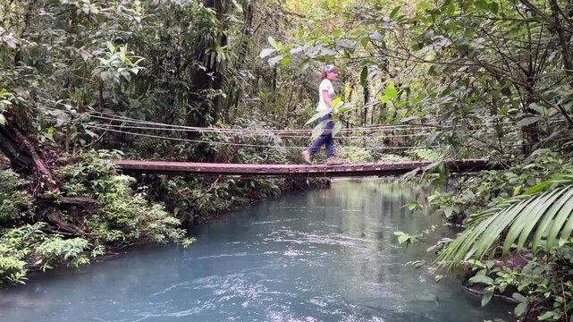 Teenager girl passing a bridge over Rio Celeste, Parco Nacional Tenorio in Costa Rica