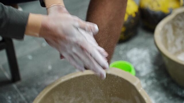 Hands of a weightlifter being covered in white chalk powder for better grip, athletic preparation, strength and power.