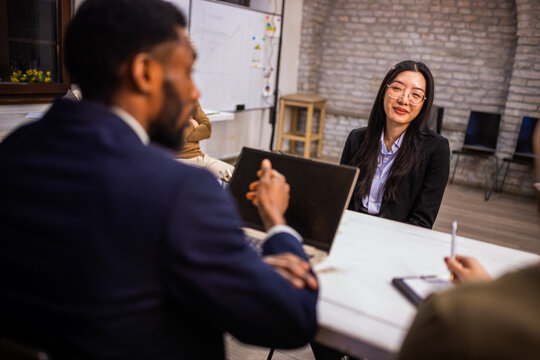 African American hiring manager interviewing a professional Asian woman in a modern office.