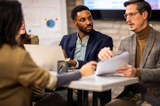 Hiring managers reviewing a resume during a job interview with a female candidate.