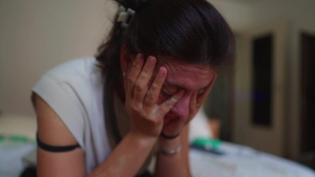 Exhausted woman sitting on bed holding head in hands showing stress burnout anxiety and emotional overwhelm during difficult moment of fatigue mental health struggle home