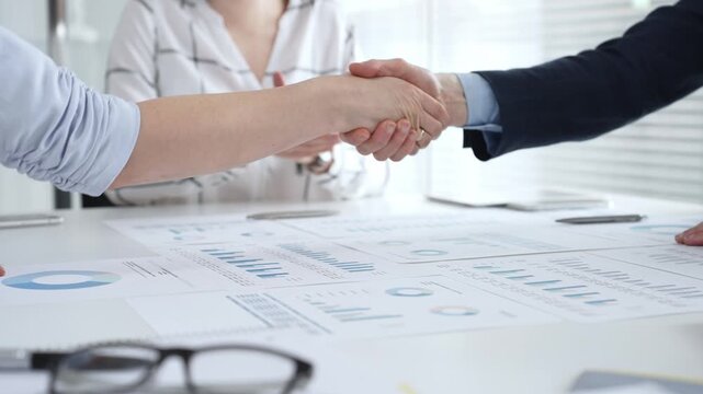 Business executives shaking hands, sealing an agreement after successful negotiations in a bright office, symbolizing partnership, collaboration, and a mutually beneficial deal signing