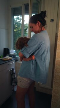 Mother breastfeeding toddler while standing in kitchen preparing meal capturing multitasking caregiving routine nourishment and everyday family life in home environment