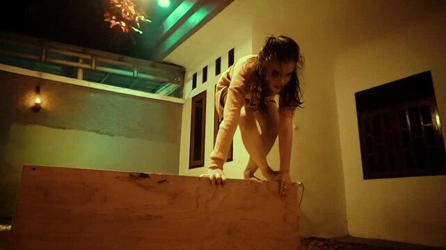Woman Precariously Balancing on a Box then Jumping Off