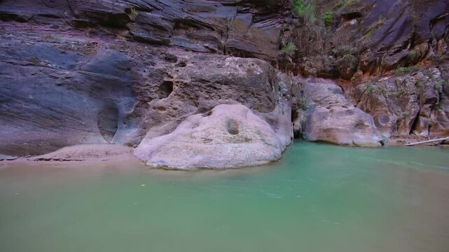 Footage of the Virgin River flowing through the stunning, thousand-foot-tall canyon walls of The Narrows in Zion National Park, Utah, USA. This iconic river trek offers breathtaking scenery and an imm