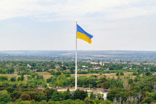 Huge Ukrainian national flag on a monumental white flagpole over Kramatorsk city park