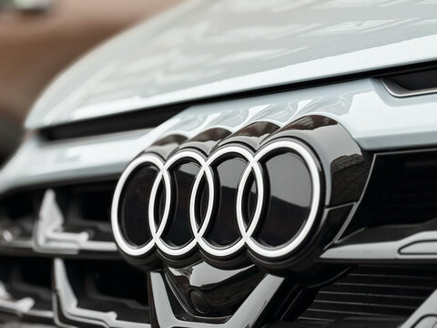 Audi A3 LED logo on the front of the gray car. Audi LED logo, close up view, car manufacturer, global automobile manufacture emblem on the radiator grille close-up. German sportback hatchback. 