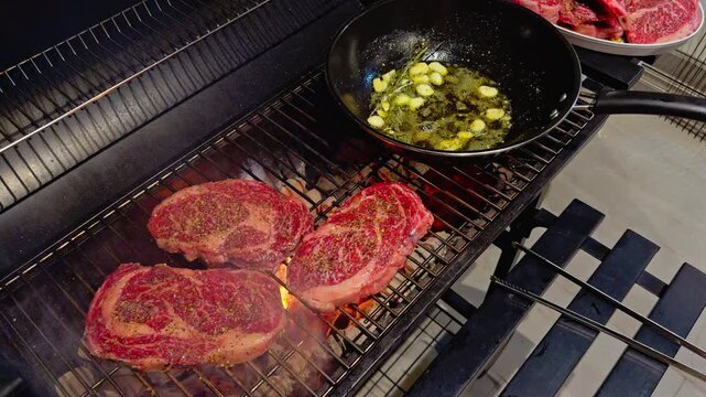 barbecue party outdoors, cooking stacks of grilled meat, rib eye steak, garlic, rosemary, butter in a pan, pieces of raw meat