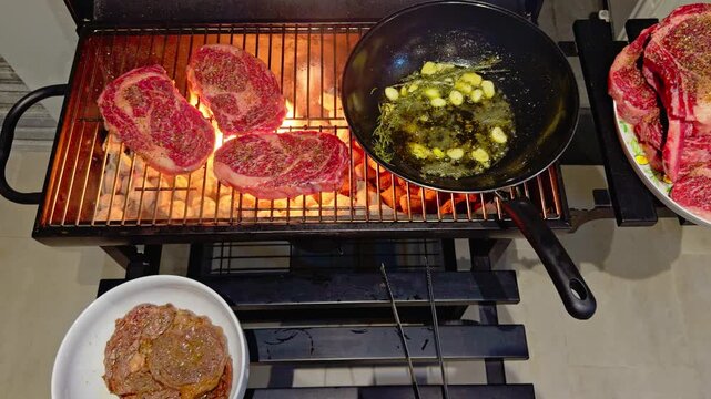 barbecue party outdoors, cooking stacks of grilled meat, rib eye steak, garlic, rosemary, butter in a pan, pieces of raw meat