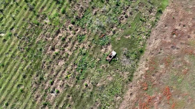 Aerial drone footage of an abandoned truck in a field riddled with shell craters, illustrating the aftermath of combat in an open area.