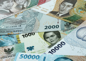 Fototapeta premium Indonesian rupiah money banknotes pile on table. Indonesia bills of IDR currency close up