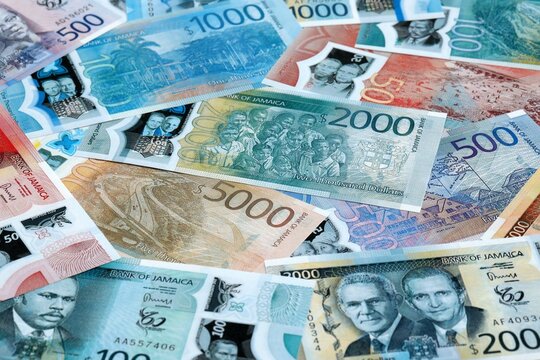 Jamaican dollar money banknotes pile on table. Jamaica bills of JMD currency close up
