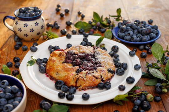 Bluebbery galette on a white ceramic plate on a wooden table. Delicious homemade pastry