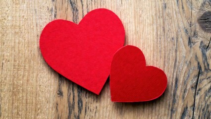 Fototapeta premium Two red felt hearts rest on rustic wood
