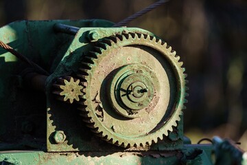 Zbliżenie na stare, zielone koła zębate i mechanizm wciągarki z liną. Detale techniczne zardzewiałej maszyny przemysłowej lub rolniczej w plenerze. © Henryk Niestrój