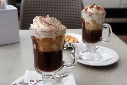Due bicchieri di tipico Bicerin torinese serviti su un tavolo all'aperto con strati di caff&egrave; espresso cioccolata calda e crema di latte