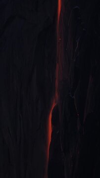 Vertical Screen: Yosemite National Park Firefall phenomenon with glowing orange waterfall cascading down dark granite rock face at twilight, creating stunning dramatic contrast