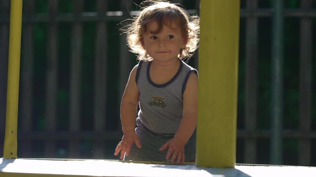 Toddler reaching toward playground merry go round with outstretched arm capturing curiosity intention and playful exploration during outdoor childhood moment in park setting