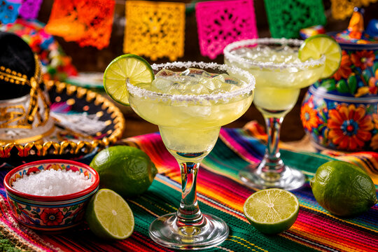 C&oacute;cteles margarita frescos con borde de lima y sal en una colorida mesa mexicana, concepto de bebida festiva para la fiesta del Cinco de Mayo y la celebraci&oacute;n de verano.