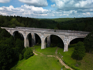 Fototapeta premium Historic concrete railway viaducts in Stanczyki surrounded by lush green forest, aerial view of monumental bridges in Rominta Forest, Poland