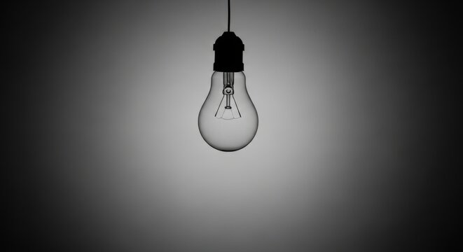 Incandescent light bulb hanging in darkness. Symbol of high electricity cost and energy crisis. Concept of rising utility bill and expensive power consumption. Financial hardship theme.