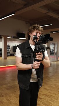Vertical screen focused videographer resists distraction while filming with camera on gimbal staying concentrated on client project despite pressure and interruptions during shooting