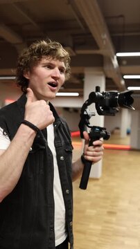 Vertical screen amazed videographer reacts to perfect shot holding camera on gimbal expressing excitement inspiration and satisfaction with captured frame during creative filming moment