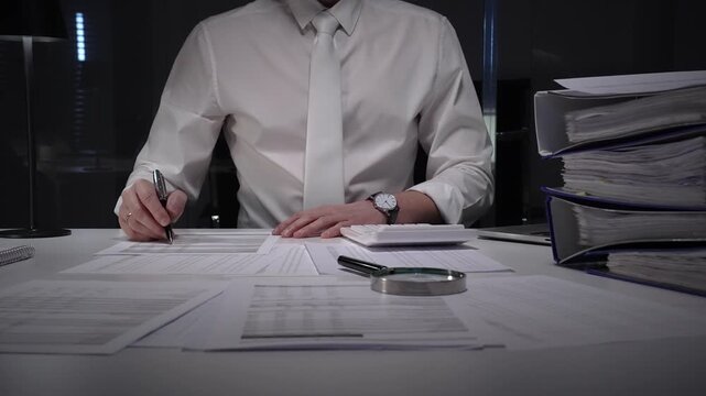 Business professional working late on financial audit in modern office, analyzing tax documents and managing paperwork deadlines with precision and expertise