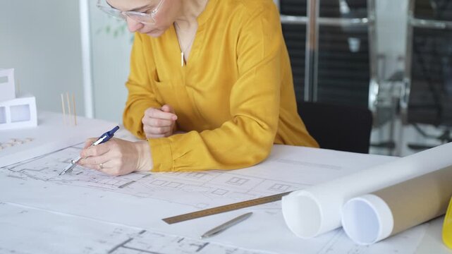 Architect hand drawing blueprints with compass tool, designing floor plans for building development. Architecture and business concept